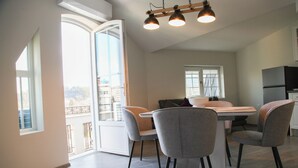 A modern kitchen with a dining area, large windows, and a view of the city. - Corner House (Lovech)
