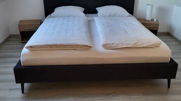 A bed with two pillows, a bedside table, and a lamp.