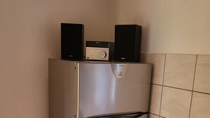 Un réfrigérateur en acier inoxydable doté d’un appareil à glaçons intégré et d’un écran numérique, placé contre un mur recouvert de carreaux.