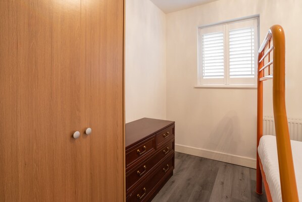 Une chambre à coucher avec une armoire en bois, une commode et un lit doté d’une tête de lit en bois.
