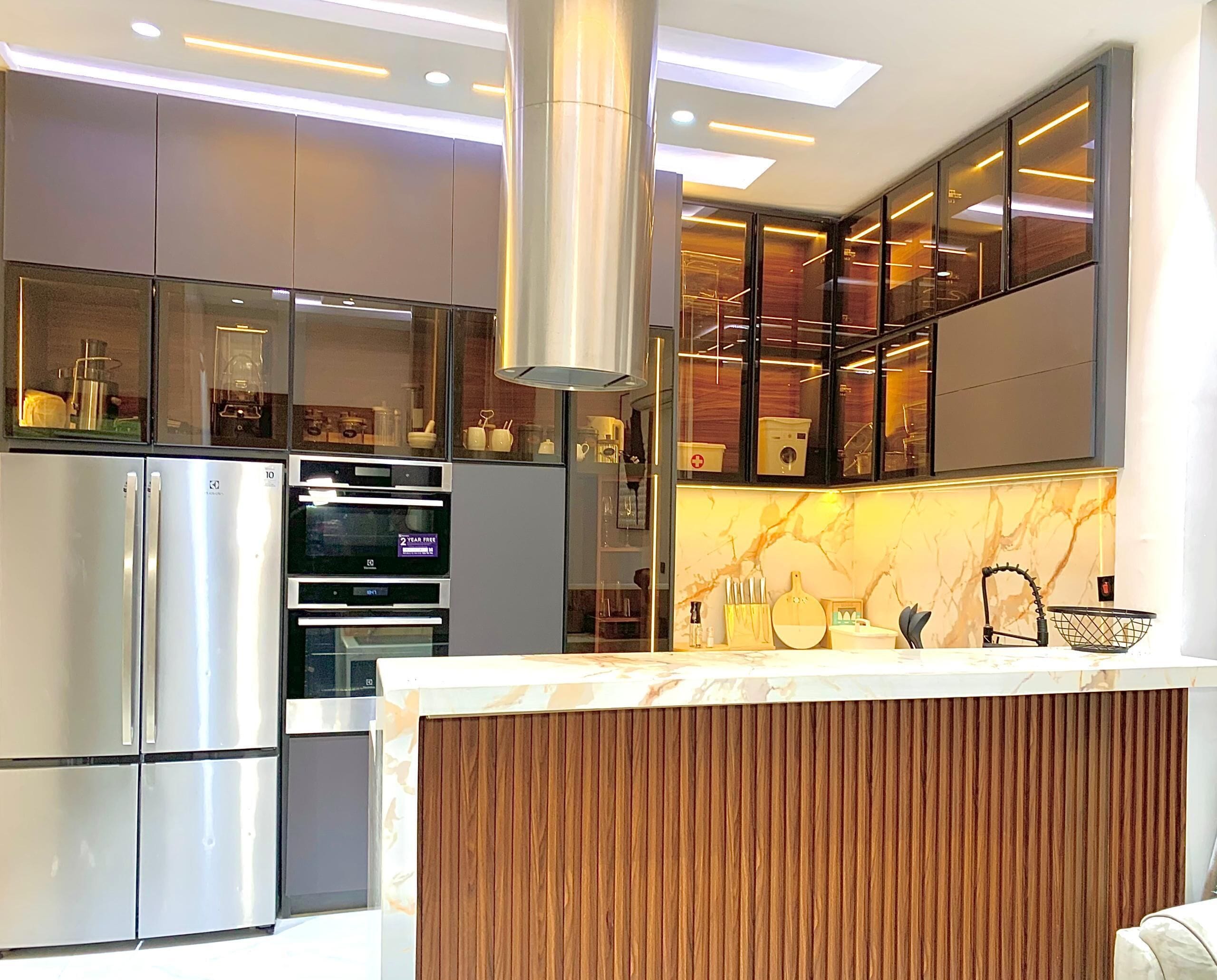 A modern kitchen with stainless steel appliances, a marble backsplash, and a wooden accent wall.