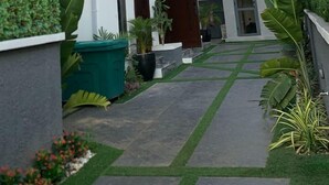 Una casa moderna de dos pisos con techo plano, ventanas amplias y un porche cubierto.
