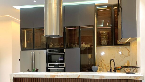 Una cocina moderna con una isla central, electrodomésticos de acero inoxidable y paneles de madera.