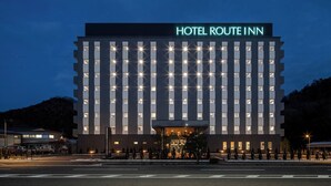 Een meerhoog hotel met een moderne gevel en een opvallend 'HOTEL ROUTE INN' bord.