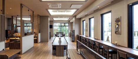 A spacious dining area with high ceilings, large windows, and a long counter with seating.