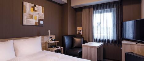 Een hotelkamer met een groot bed, een bureau, een stoel, een televisie en een raam met gordijnen.