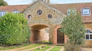 A stone building with a tiled roof, a central archway, and a bell tower. - Host Stay The Clock Tower (King's Lynn)