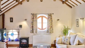 A cozy living room with a wooden ceiling, a fireplace, a round glass table, and a white sofa. - Host Stay The Clock Tower (King's Lynn)