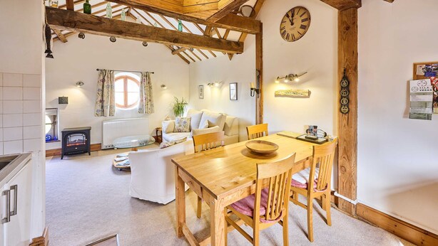 A cozy room with a wooden dining table, chairs, a sofa, and a window with curtains. - Host Stay The Clock Tower (King's Lynn)