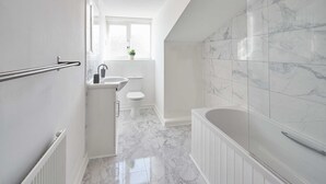 Uma casa de banho moderna com banheira, sanita e lavatório.