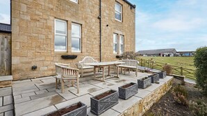 A stone building with a patio area featuring outdoor furniture and planters. - Host Stay Mount Cottage (Newcastle-upon-Tyne)