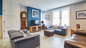 A living room with a large window, a television, a clock, and a framed picture on the wall. - Host Stay Mount Cottage (Newcastle-upon-Tyne)