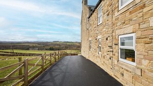 A stone building with a paved walkway leading to a wooden fence overlooking a rural landscape. - Host Stay Mount Cottage (Newcastle-upon-Tyne)