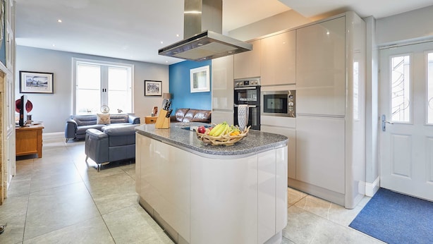 A modern kitchen with white cabinets, a central island, and a built-in oven. - Host Stay Mount Cottage (Newcastle-upon-Tyne)