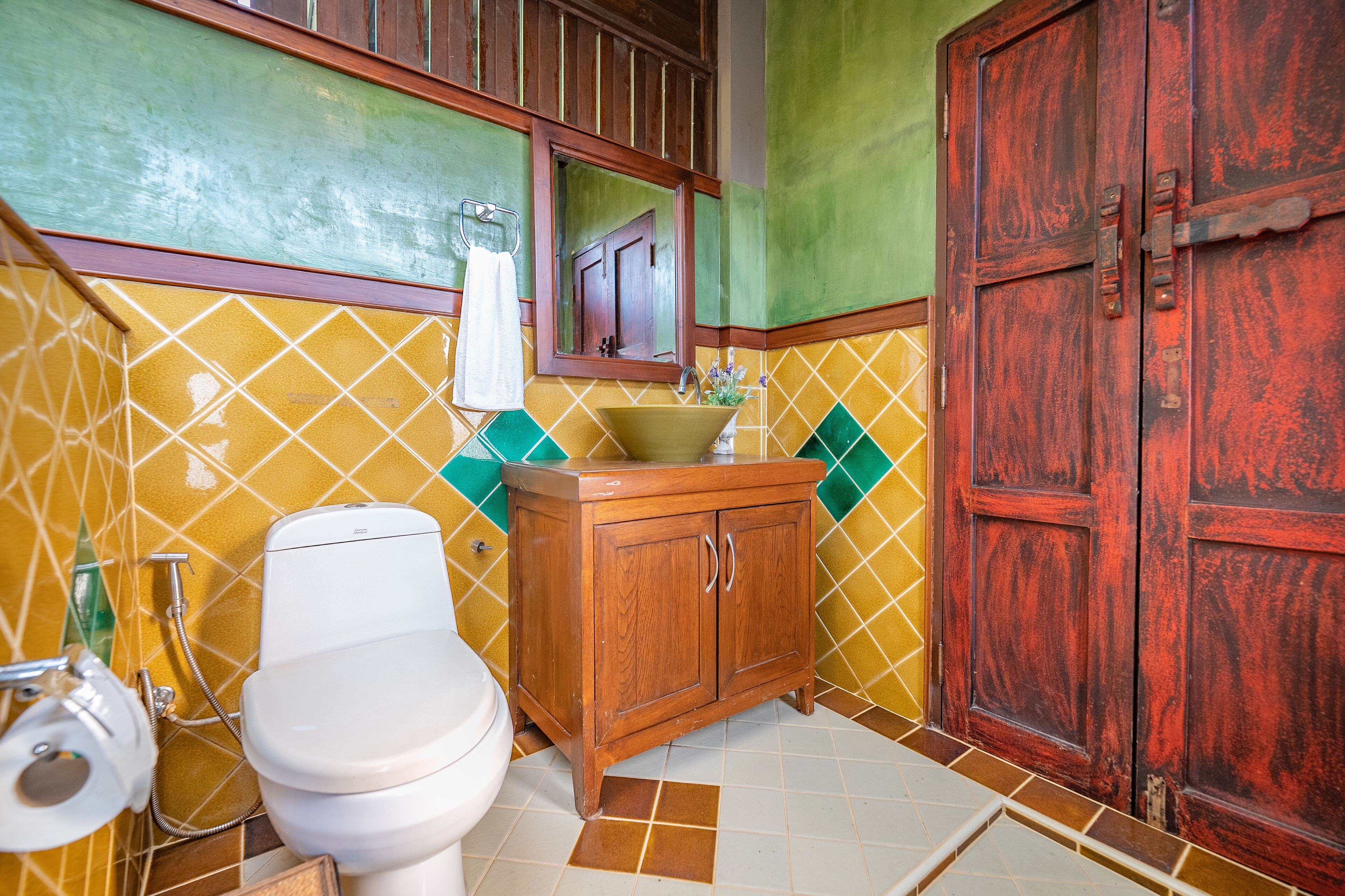 A bathroom with a toilet, sink, wooden cabinet, and a large wooden door.