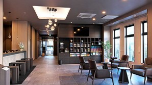 A modern hotel lobby with a reception desk, seating area, and a display of amenities.