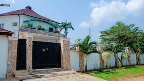 Uma casa de dois andares com telhado curvo, varanda e portão.