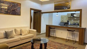 Uma sala de estar moderna com sofá, mesa de centro e área de cozinha com banquetas.