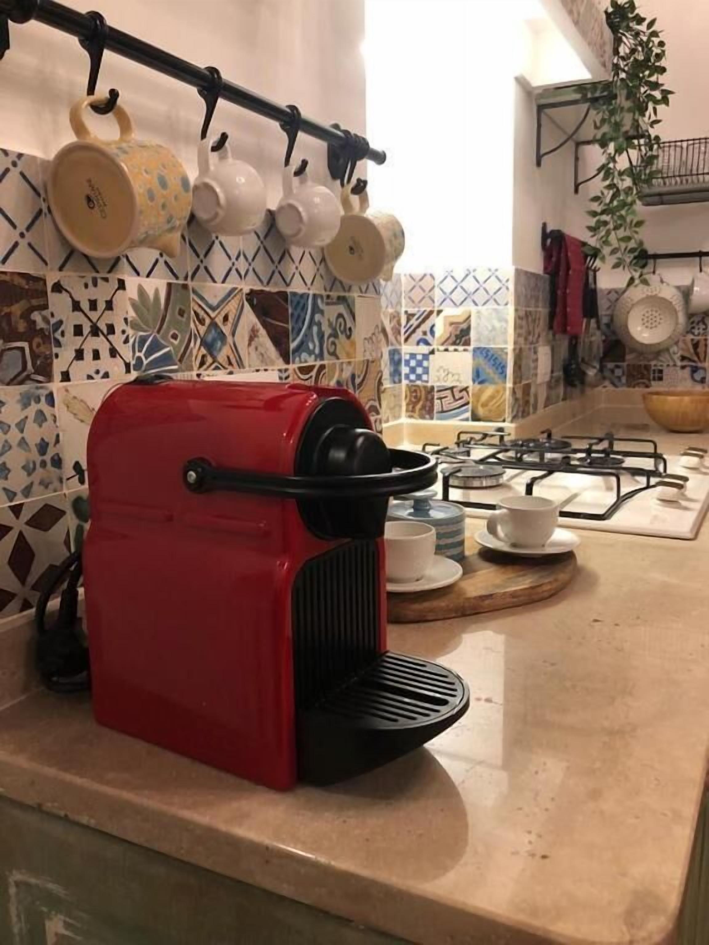A kitchen with a red coffee maker, a gas stove, and a tiled backsplash.
