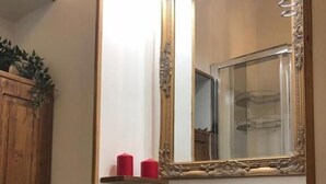 A bathroom with a large mirror, a white sink, and wooden shelves with candles.