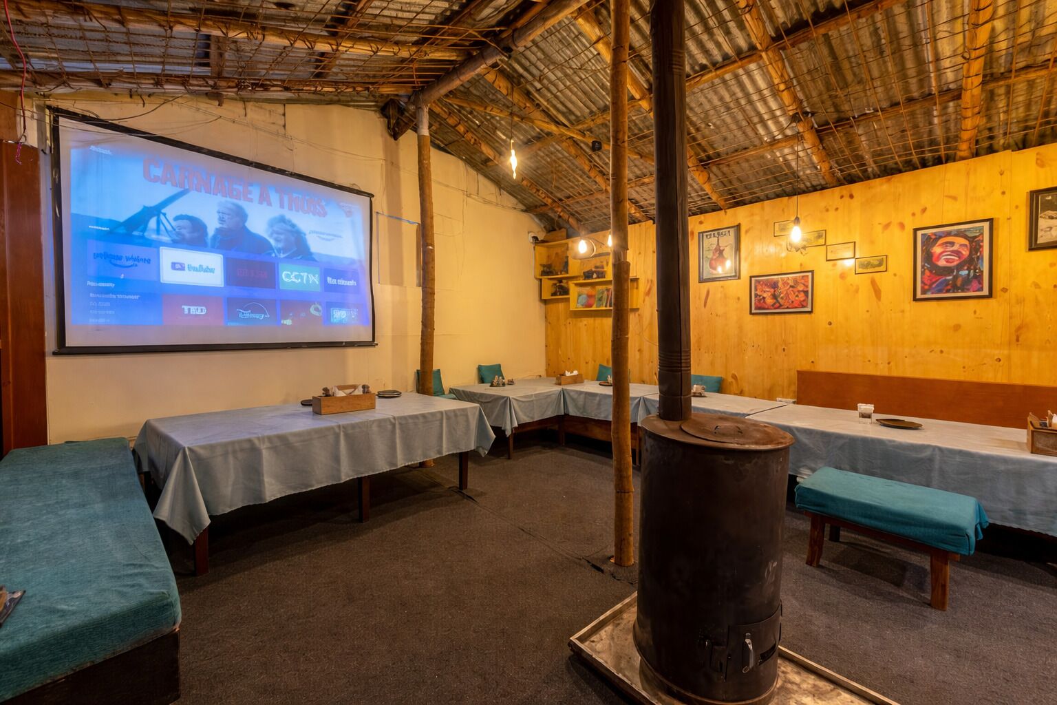 A conference room with a large screen displaying a presentation, tables with white tablecloths, and a large cylindrical heater.