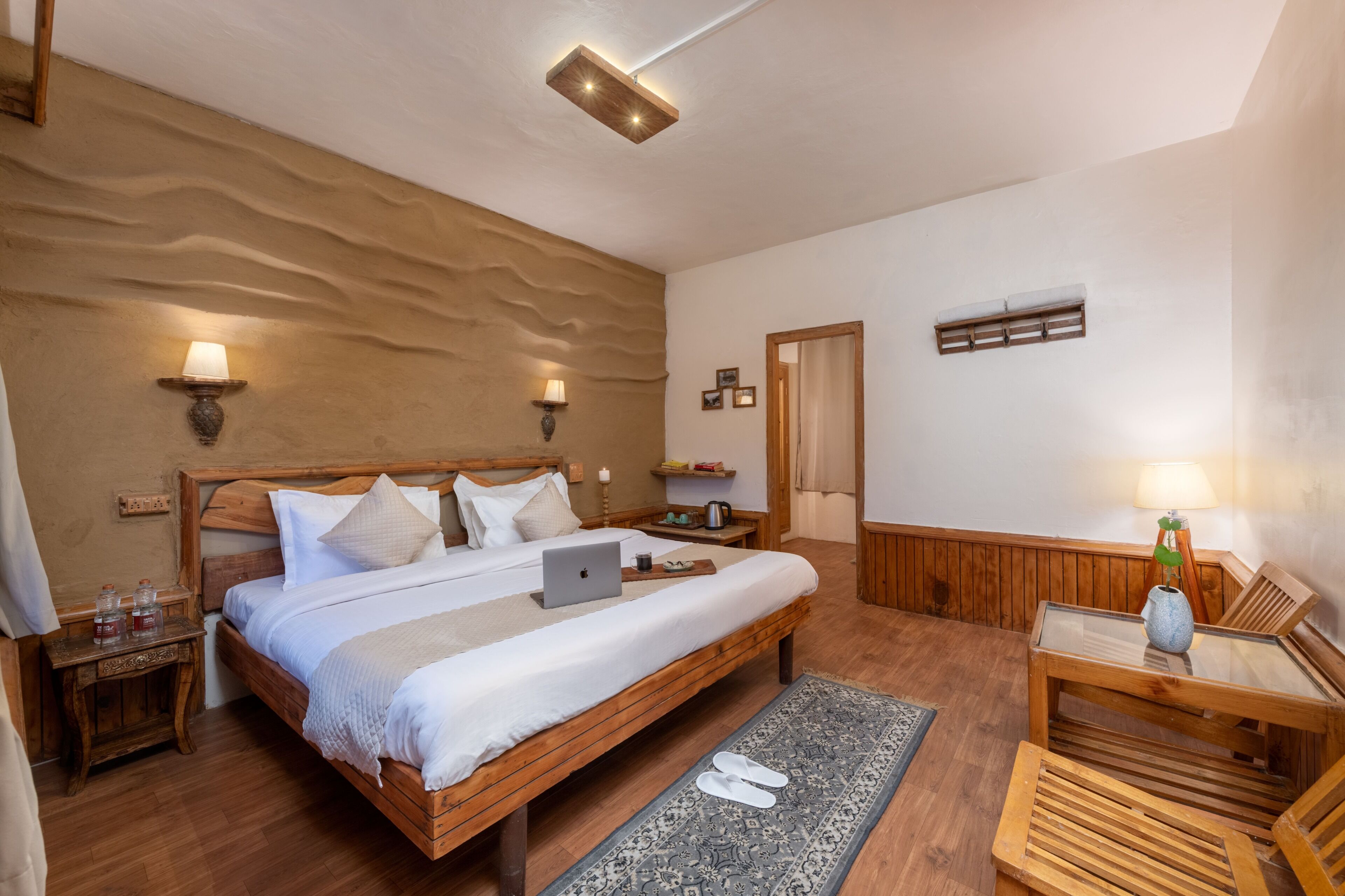 Una camera da letto con un letto di legno, un laptop, comodini, uno specchio e un tavolino con una lampada.