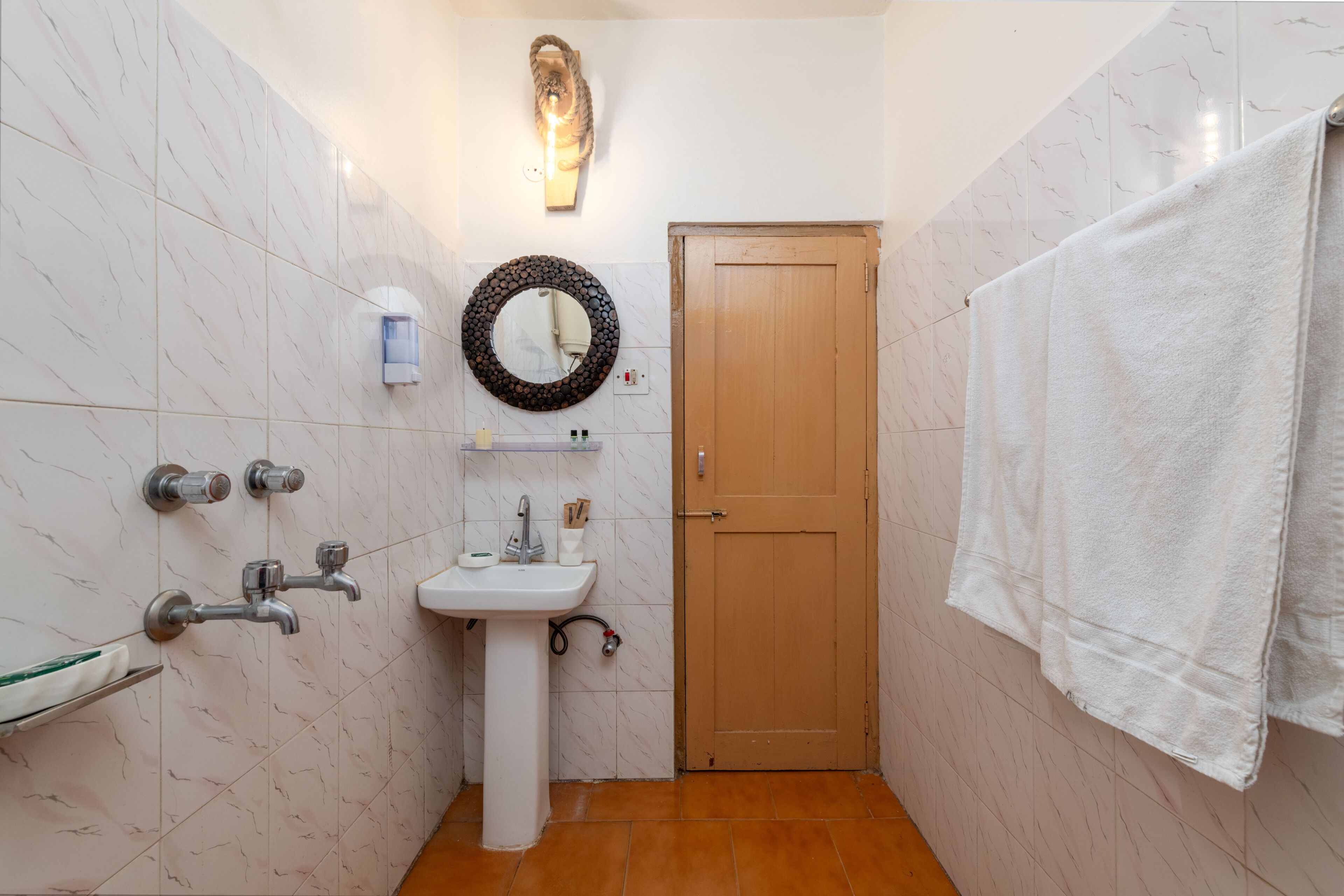 A bathroom with a sink, mirror, towel rack, and a wooden door.