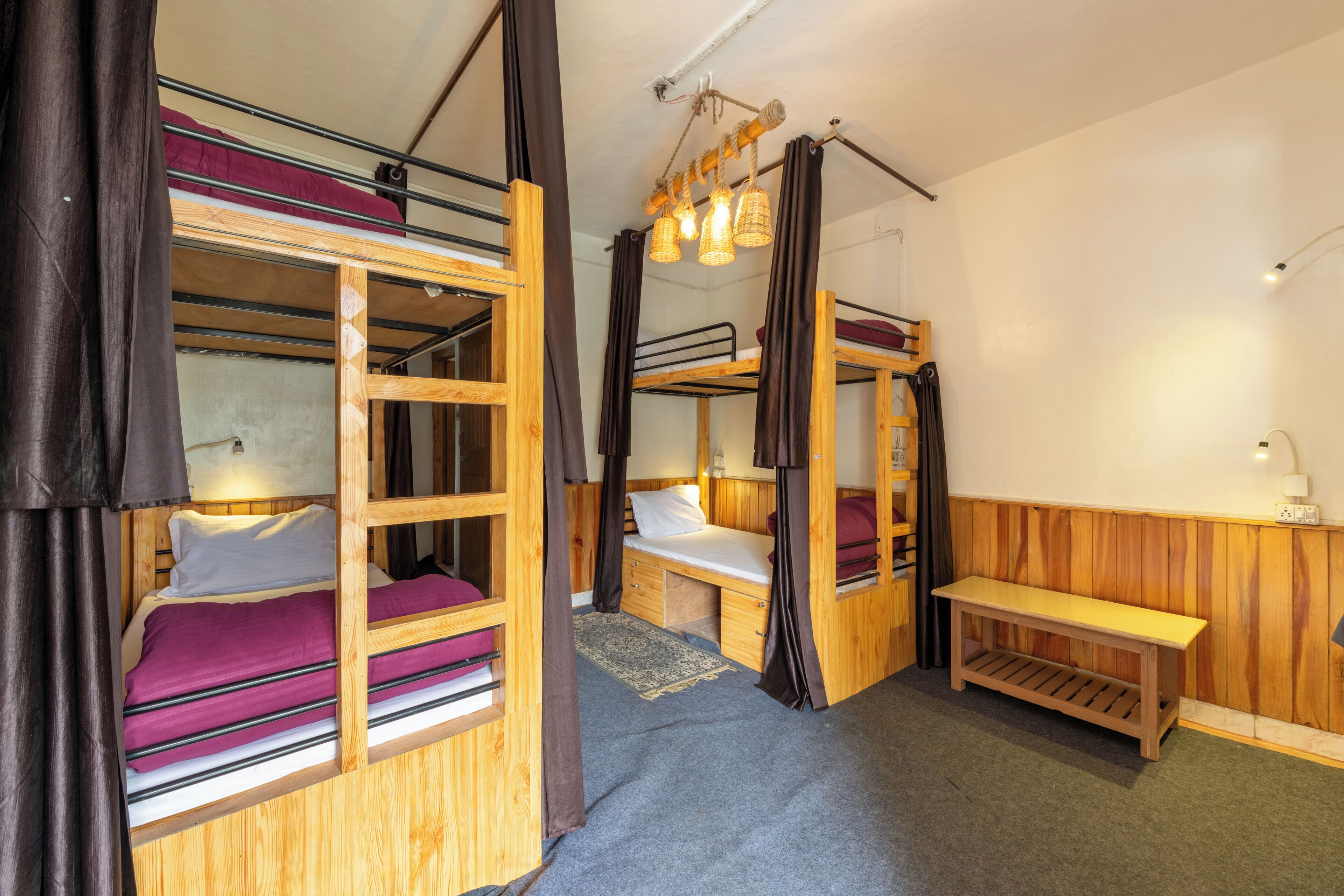 A room with bunk beds, a bench, a small table, and a hanging light fixture.