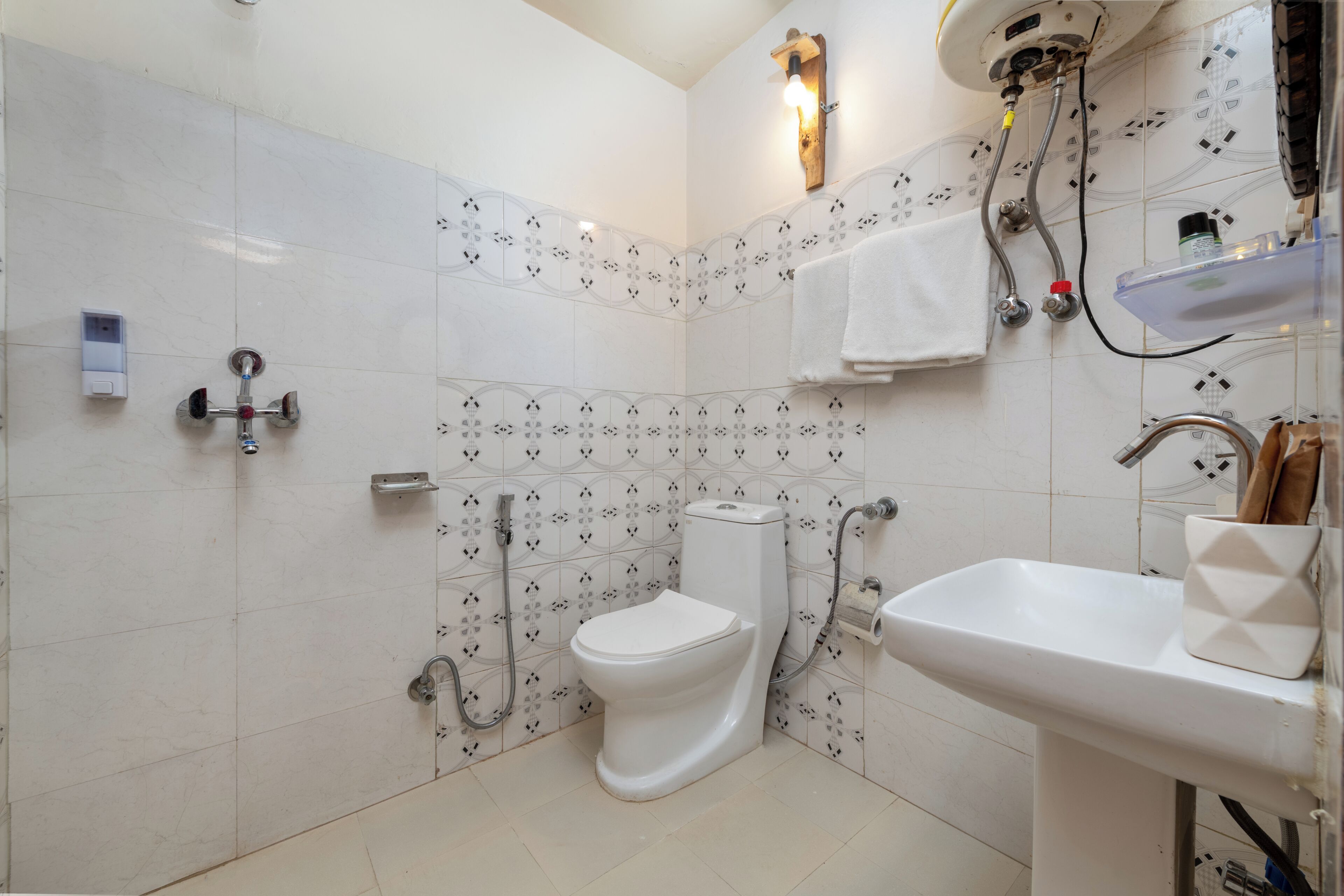 Une salle de bain équipée de toilettes, d’une douche, d’un lavabo et de carreaux décoratifs.