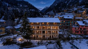 A multi-story hotel with balconies, surrounded by snow-covered mountains. - Beholden Stay & Cafe-Mountain View Boutique Stay in Old Manali (Manali)
