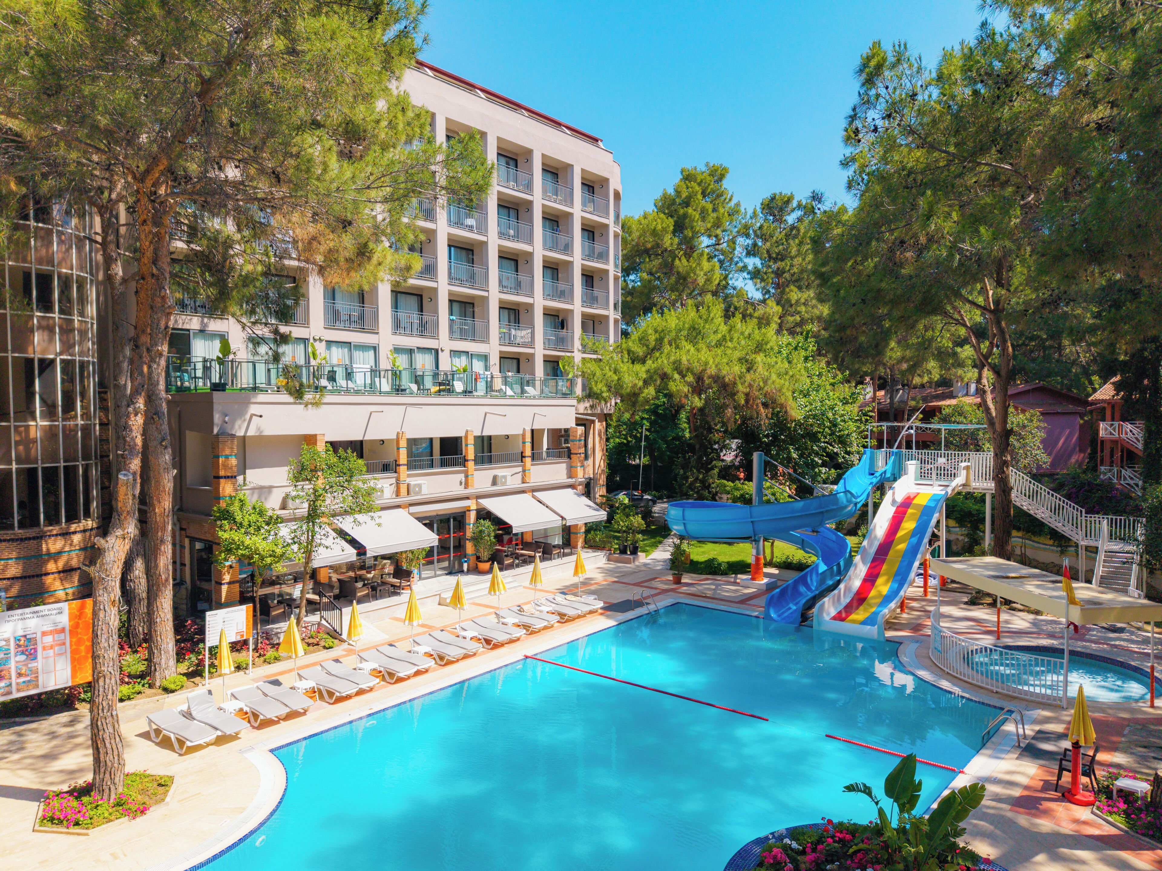 A hotel with a swimming pool, lounge chairs, and a water slide.