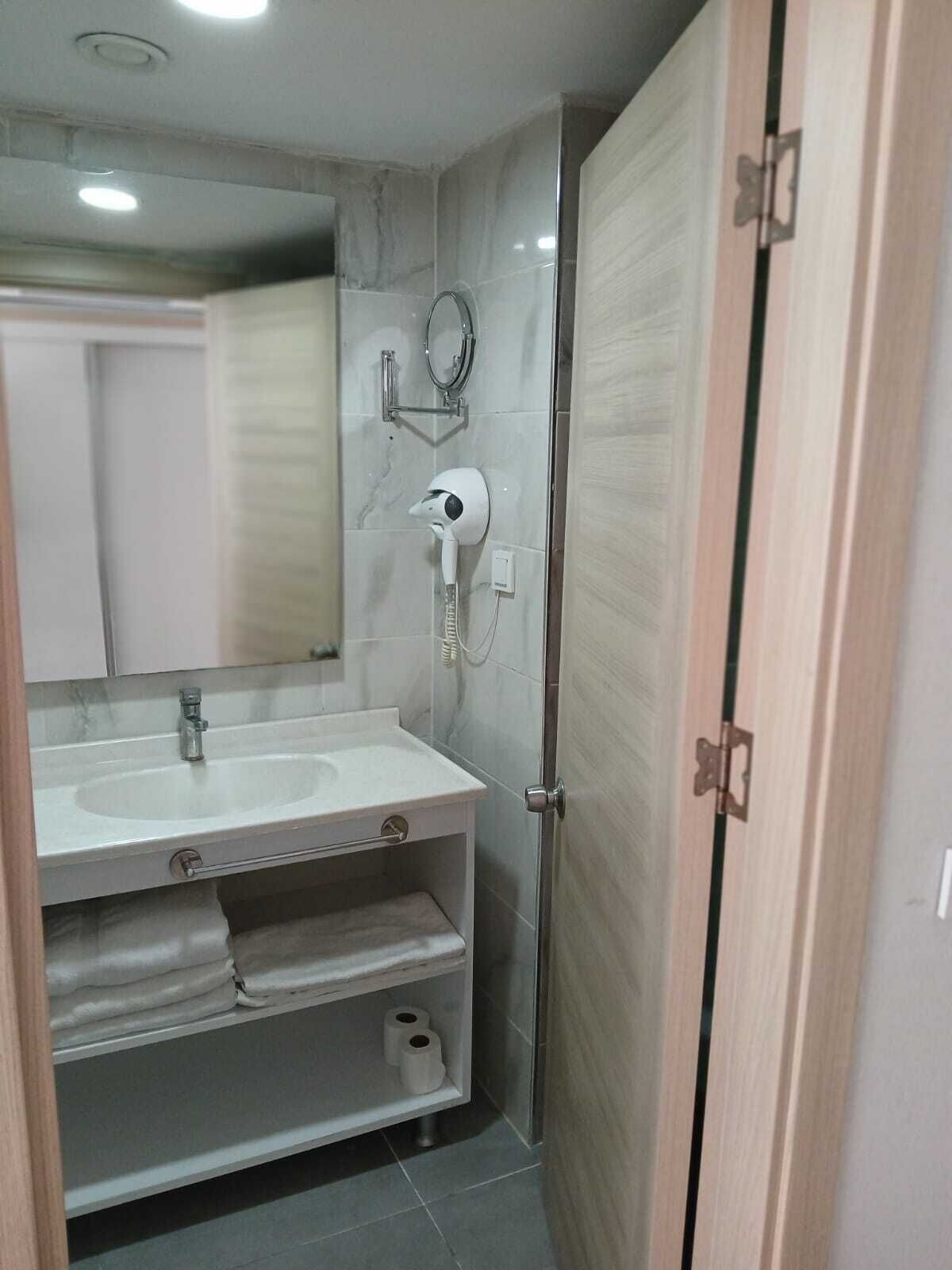 A modern bathroom with a white sink, mirror, and towel rack.