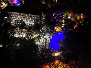 An aerial view of a hotel with multiple floors, outdoor seating areas, and a pool.