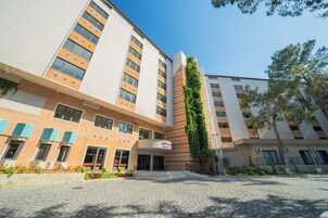 Un hotel de varios pisos con fachada de ladrillo, ventanas amplias y un jardín vertical.