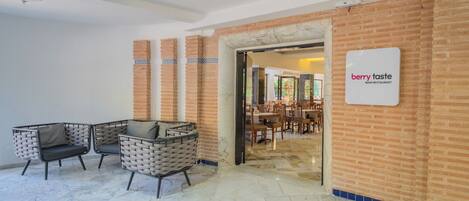 A modern interior with a reception area, a sign for 'berry taste' main restaurant, and a seating area with chairs and a table.