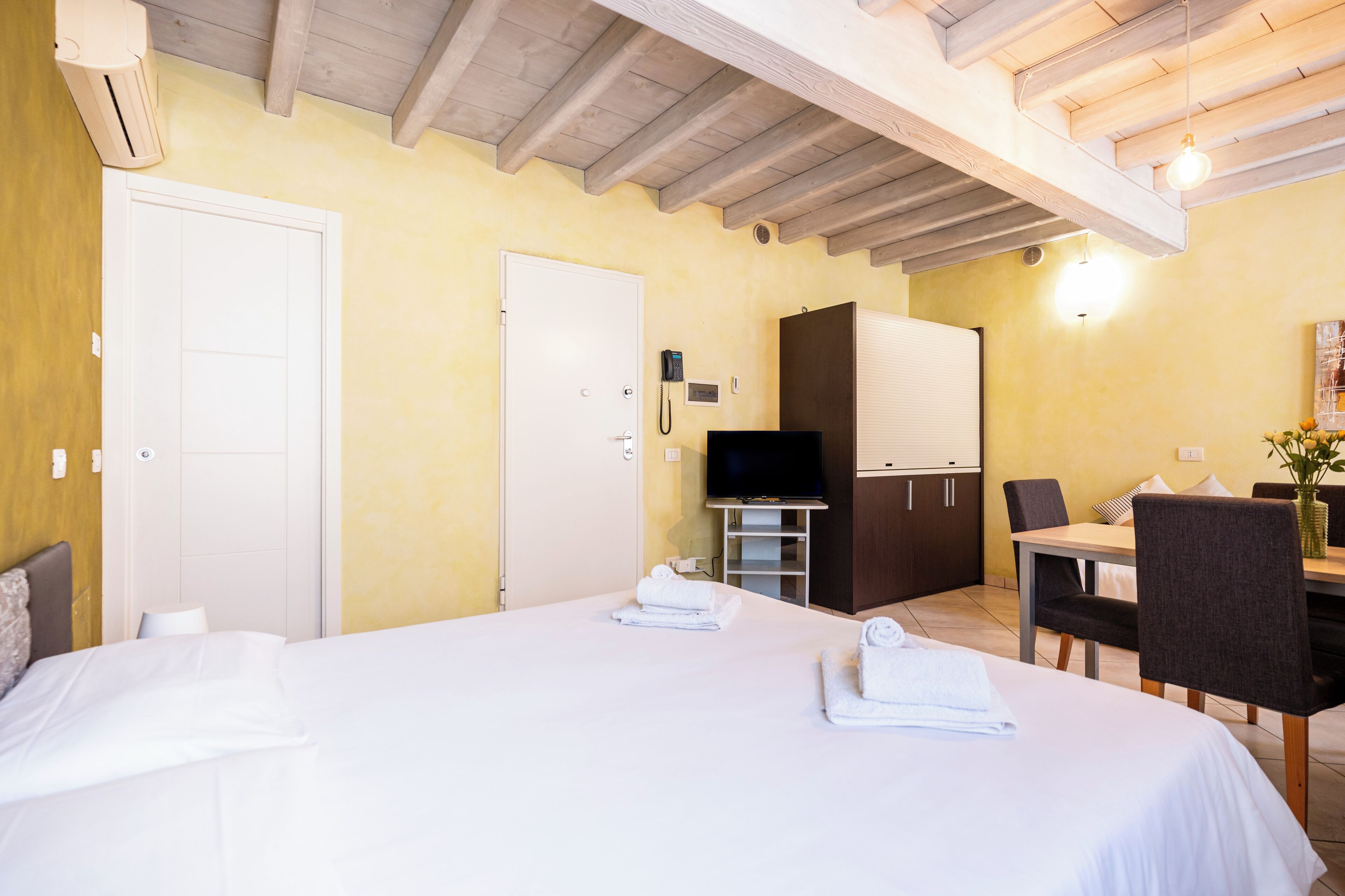 Ein Hotelzimmer mit Bett, Schreibtisch, Stuhl, Fernseher und einer Tür.