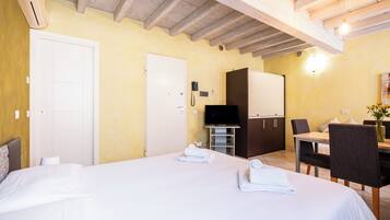Ein Hotelzimmer mit Bett, Schreibtisch, Stuhl, Fernseher und einer Tür.