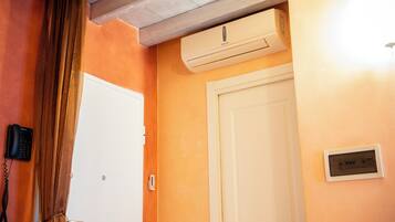 A room with an air conditioning unit, a white door, and a telephone on the wall.