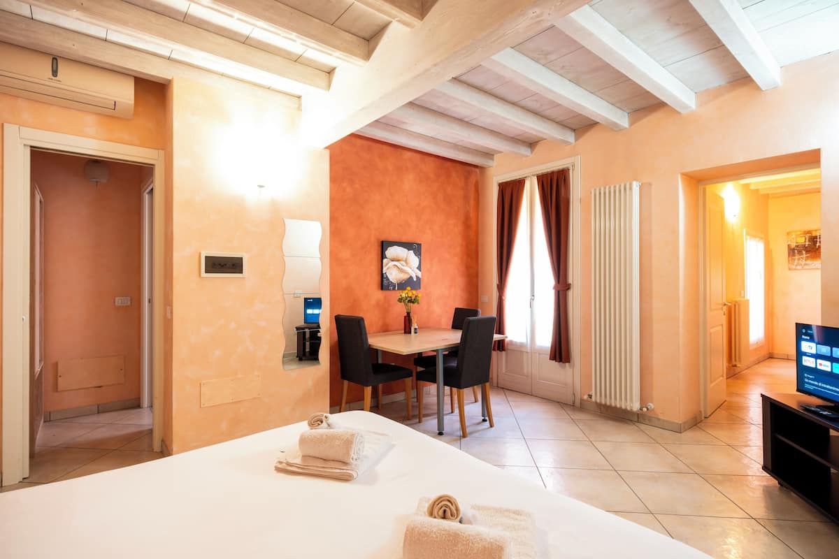 A hotel room with a bed, a dining table with chairs, a television, and a bathroom with a shower.