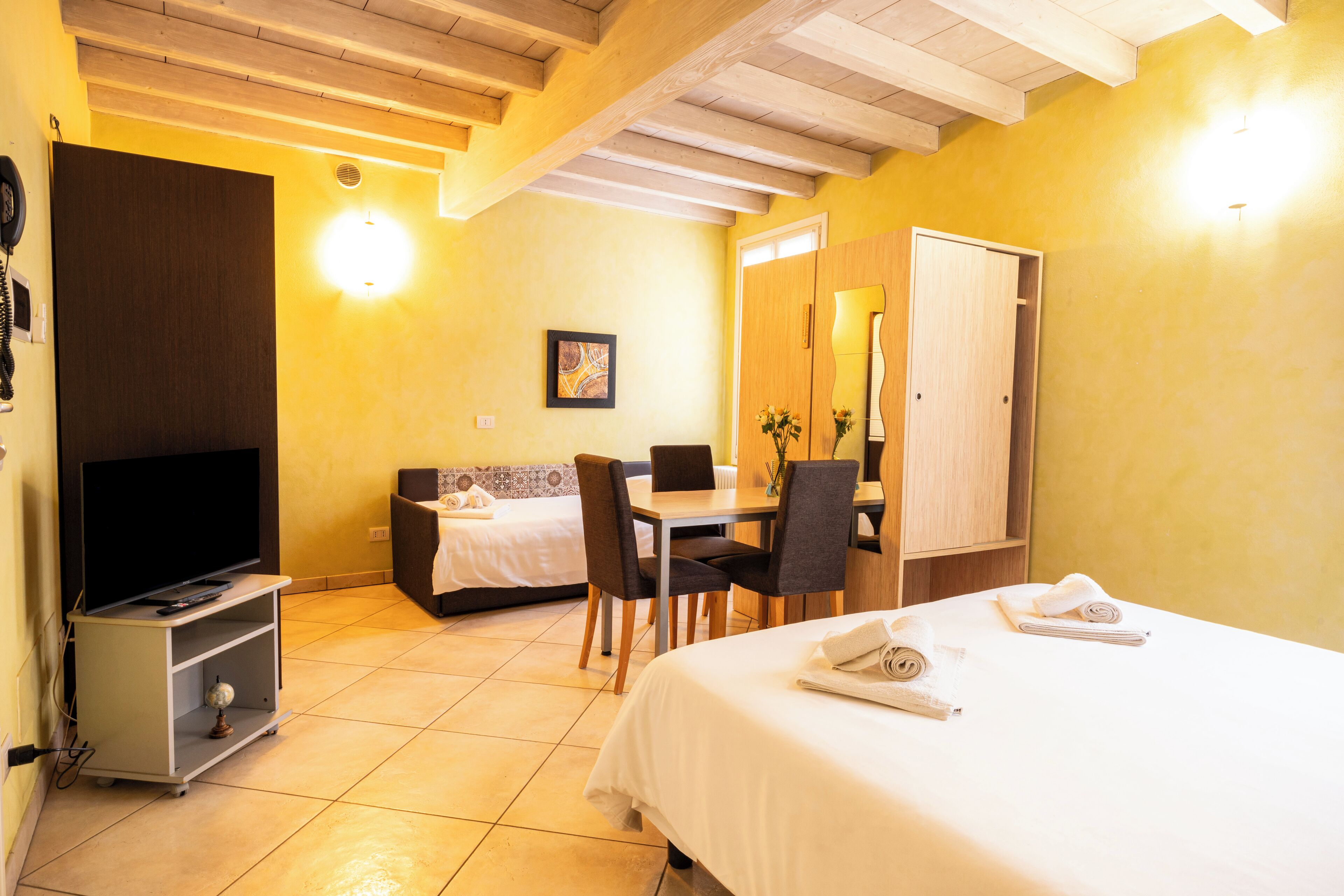 Habitació d'hotel amb llit, escriptori, cadira, televisió i bany.