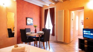 A hotel room with a dining area, a bed, a TV, and a window with curtains. - Al Podestà (Mantua)