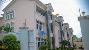 A multi-story residential building with a symmetrical facade, large windows, and a gated entrance. - Hillview Apartments (Abuja)