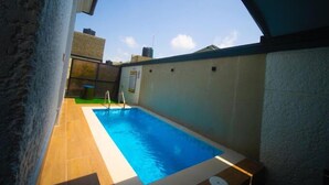 A small indoor swimming pool with a clear view of the sky and surrounding buildings. - Hillview Apartments (Abuja)