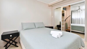 A bedroom with a bed, a nightstand, a wardrobe, and a mirror.