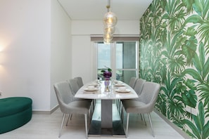 Un espace repas avec une table blanche, des chaises grises et un luminaire suspendu.