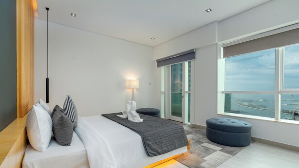 A modern hotel room with a large bed, a view of the city, and a large window. - Samaya Holiday Homes - Marina luxury Suites (Dubai)