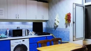 Cuina compacta amb rentadora, microones i zona de menjador amb taula i cadires.
