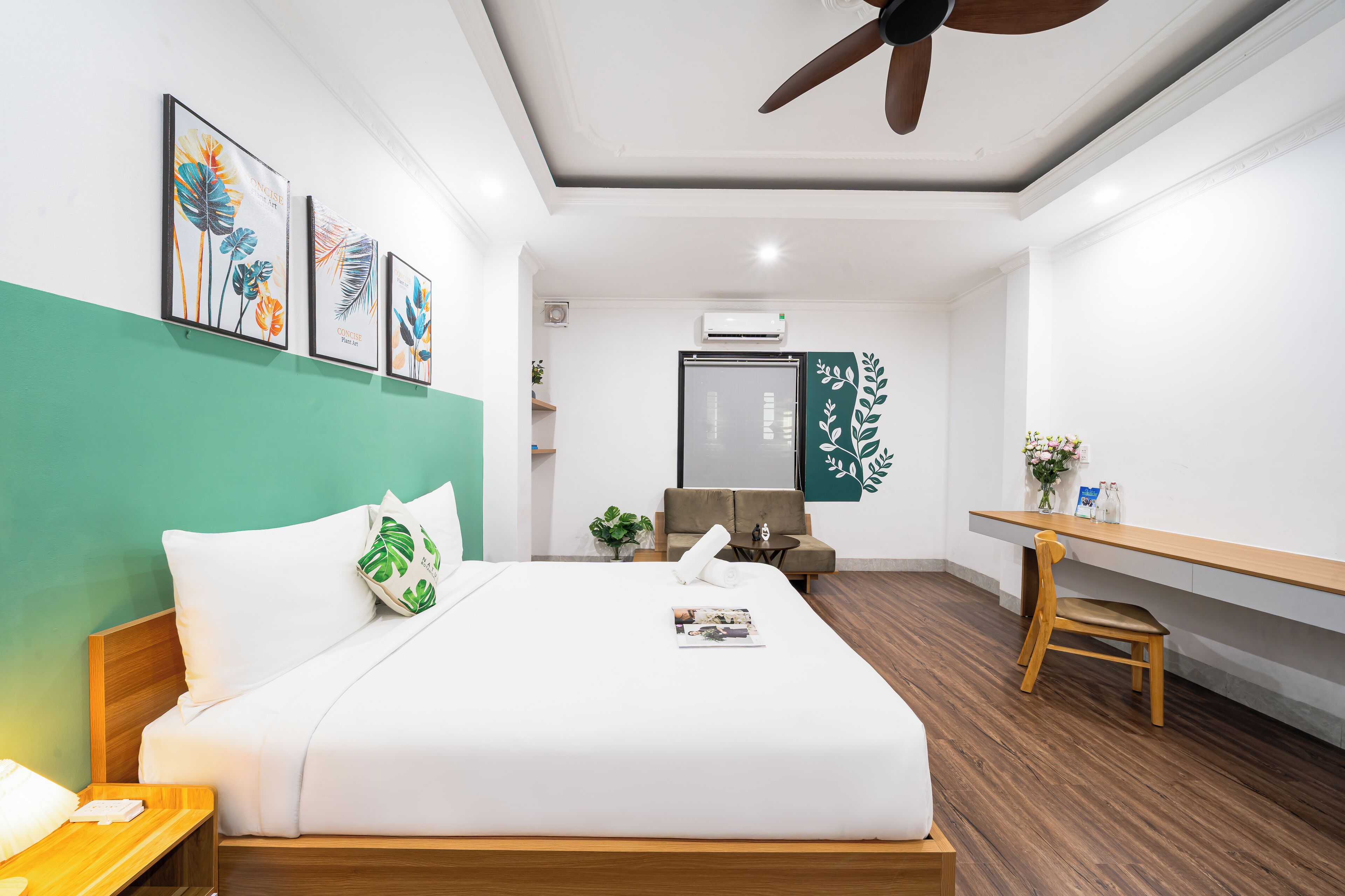 Een moderne hotelkamer met een bed, een bureau en een plafondventilator.