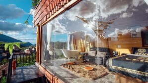 Una habitación moderna con un gran ventanal, una bañera y un manto de piel.