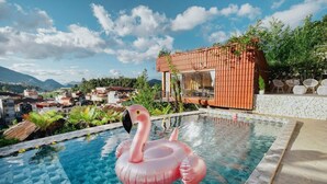 Una piscina con un flotador de flamenco rosa, rodeada por un muro de piedra y una terraza de madera.